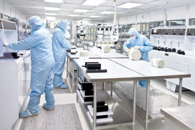 Sala limpa moderna com controle avançado de pressão e qualidade do ar, mostrando técnico ajustando painel eletrônico e filtros de ar no teto.